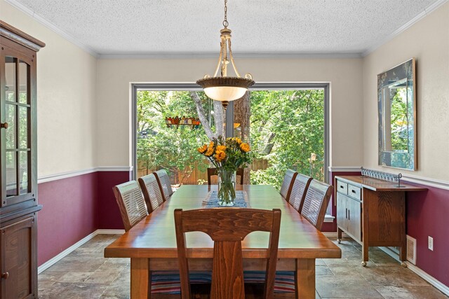 tiled dining space featuring a textured ceiling, crown molding, and a healthy amount of sunlight