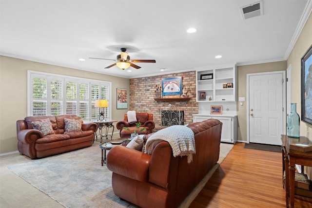 living room with ceiling fan, built in shelves, light wood-type flooring, ornamental molding, and a fireplace