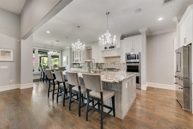 kitchen with an inviting chandelier, tasteful backsplash, appliances with stainless steel finishes, and white cabinets