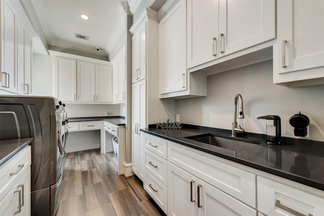 kitchen with dark countertops, visible vents, a sink, and white cabinetry