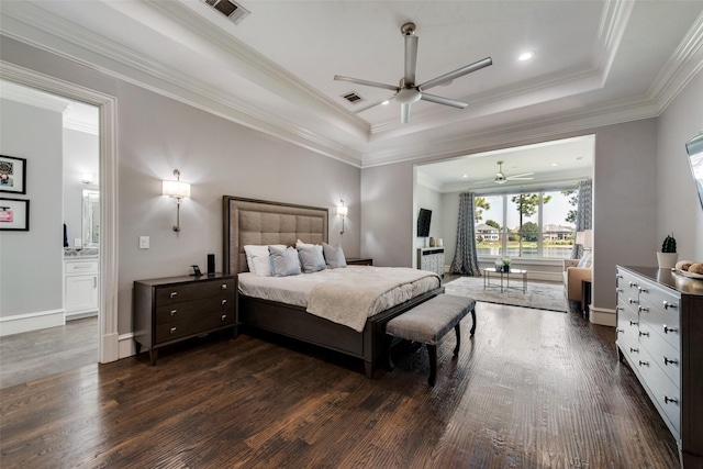 bedroom with a tray ceiling, dark wood-style flooring, visible vents, and crown molding