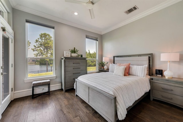 bedroom featuring a water view, visible vents, baseboards, dark wood finished floors, and crown molding