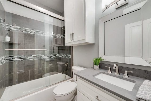 bathroom featuring enclosed tub / shower combo, vanity, and toilet