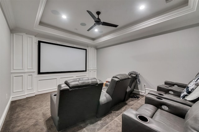 home theater with carpet floors, crown molding, a raised ceiling, a ceiling fan, and baseboards