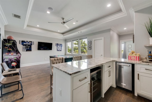 kitchen with a raised ceiling, white cabinetry, beverage cooler, and a peninsula