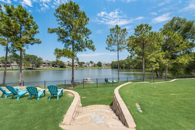 surrounding community featuring a water view, fence, and a lawn