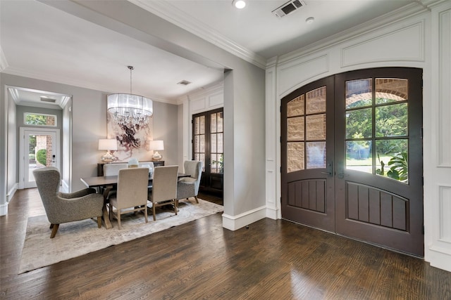 foyer entrance with crown molding, dark wood-type flooring, visible vents, french doors, and an inviting chandelier