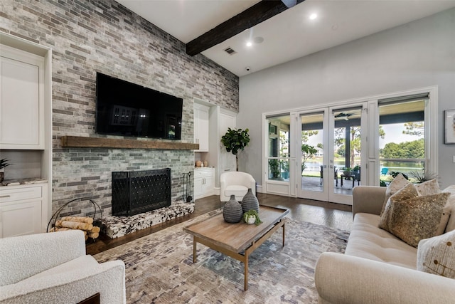 living room with french doors, visible vents, a brick fireplace, wood finished floors, and beamed ceiling