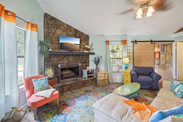 tiled living room featuring ceiling fan, a fireplace, lofted ceiling, and a barn door