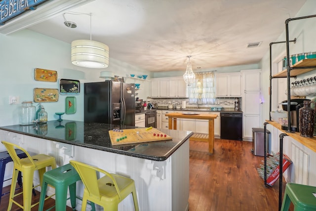 kitchen featuring decorative light fixtures, kitchen peninsula, black appliances, and dark hardwood / wood-style floors