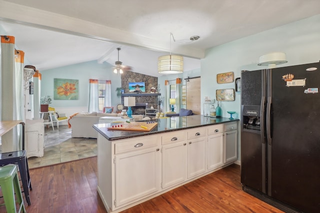 kitchen with black refrigerator with ice dispenser, lofted ceiling with beams, dark hardwood / wood-style floors, and a fireplace