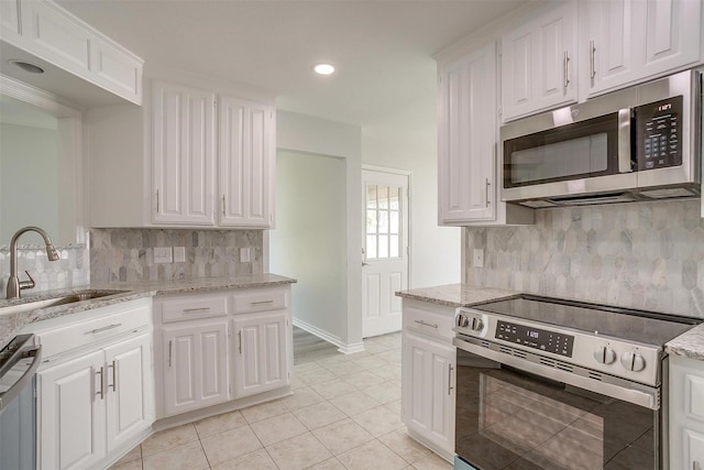 kitchen with appliances with stainless steel finishes, white cabinetry, a sink, and light tile patterned floors