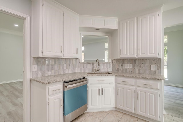 kitchen with tasteful backsplash, white cabinets, crown molding, stainless steel dishwasher, and a sink