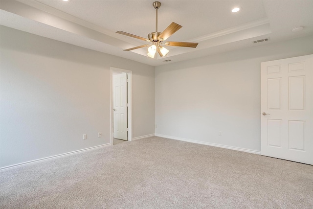 spare room with carpet floors, a raised ceiling, visible vents, and baseboards