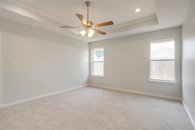 spare room with a textured ceiling, recessed lighting, carpet floors, baseboards, and a tray ceiling