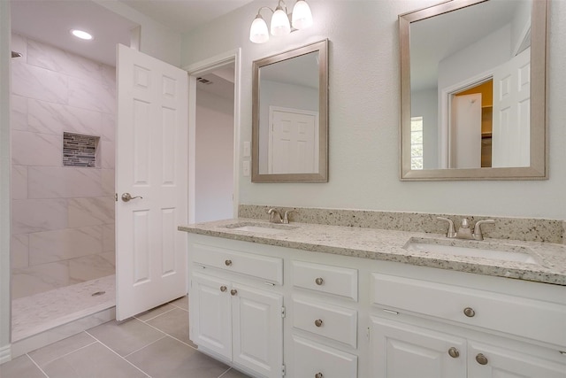 bathroom featuring double vanity, tile patterned flooring, a sink, and tiled shower