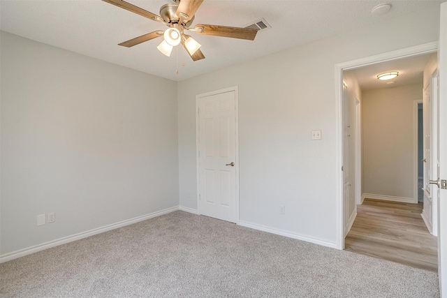 unfurnished bedroom with light carpet, baseboards, visible vents, and ceiling fan