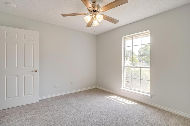 carpeted empty room featuring a textured ceiling, a ceiling fan, and baseboards