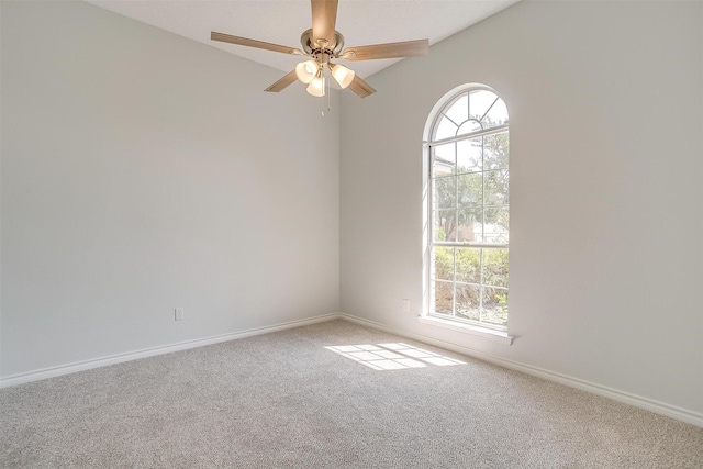 carpeted spare room with a ceiling fan and baseboards