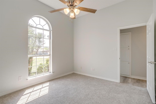 empty room with ceiling fan, baseboards, and light colored carpet