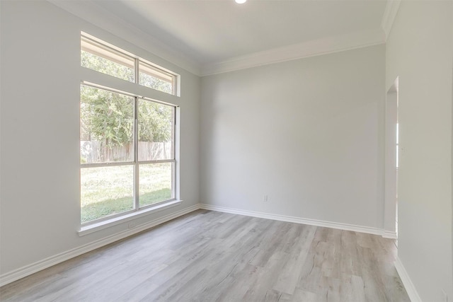 unfurnished room featuring baseboards, light wood finished floors, and crown molding