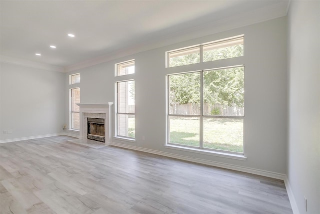 unfurnished living room featuring a tiled fireplace, ornamental molding, plenty of natural light, and baseboards