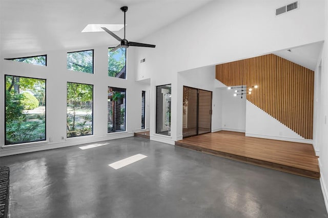 unfurnished living room with ceiling fan, a skylight, concrete floors, and high vaulted ceiling