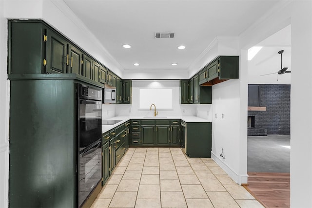 kitchen with sink, green cabinetry, a fireplace, and ceiling fan