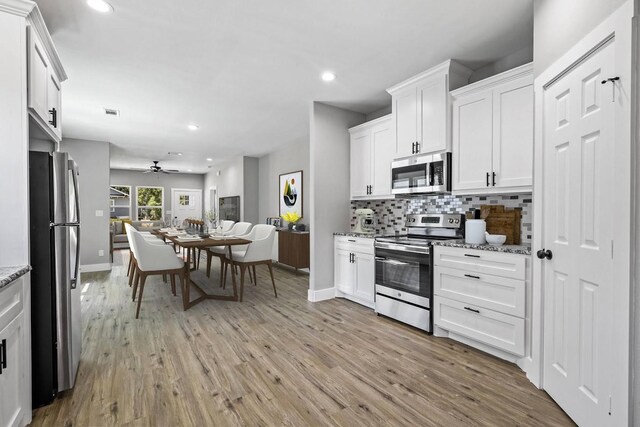 kitchen featuring stainless steel appliances, light hardwood / wood-style flooring, light stone counters, and white cabinets