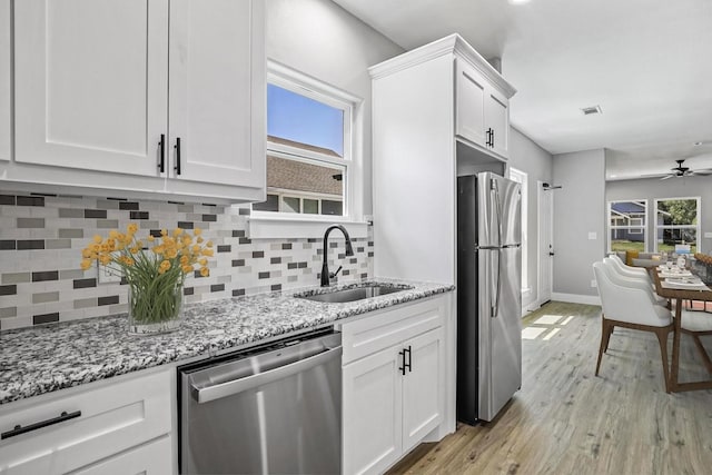 kitchen featuring light stone counters, a sink, white cabinetry, appliances with stainless steel finishes, and light wood-type flooring