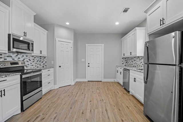 kitchen featuring appliances with stainless steel finishes, tasteful backsplash, light wood-type flooring, and light stone countertops