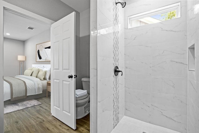 bathroom featuring toilet, tiled shower, and hardwood / wood-style flooring