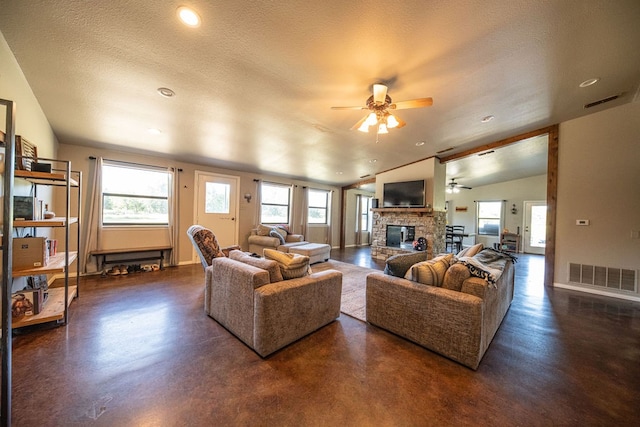 living room with a textured ceiling, ceiling fan, lofted ceiling, and a fireplace