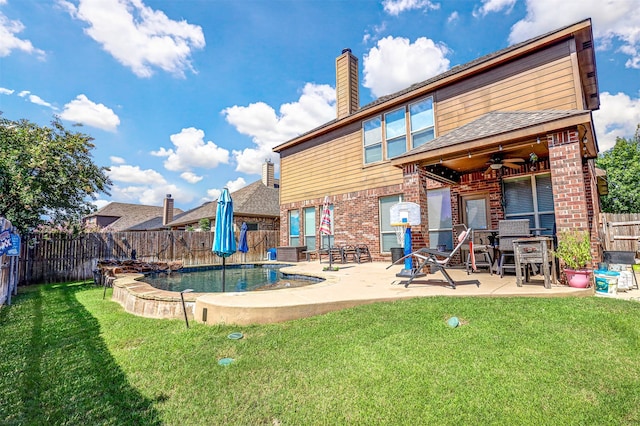 back of property with ceiling fan, a yard, a patio area, and a fenced in pool