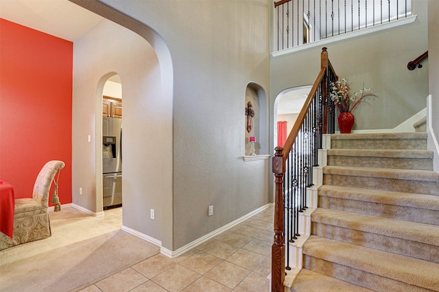 staircase featuring a towering ceiling and tile patterned floors