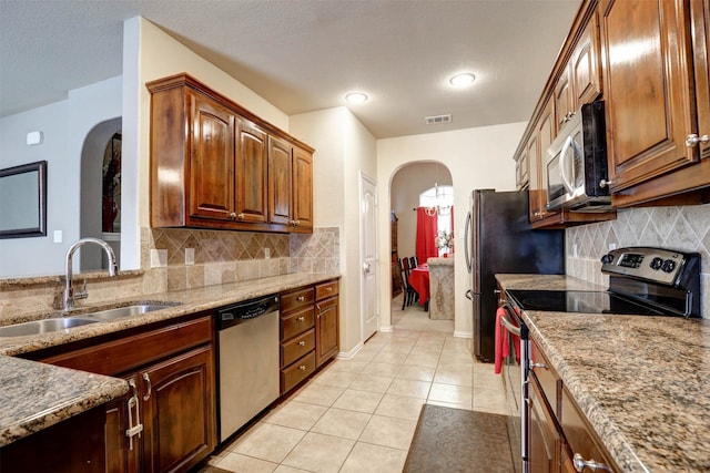 kitchen featuring appliances with stainless steel finishes, light tile patterned flooring, sink, and backsplash