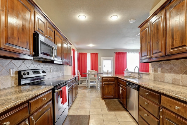 kitchen featuring stainless steel appliances, tasteful backsplash, sink, light stone counters, and light tile patterned floors