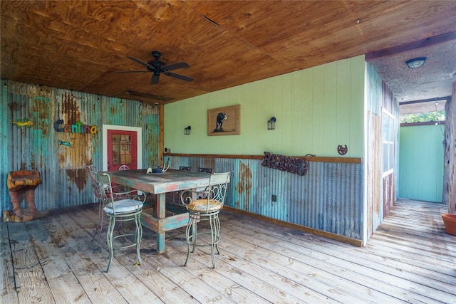 dining room with ceiling fan, wooden walls, wooden ceiling, and light hardwood / wood-style flooring