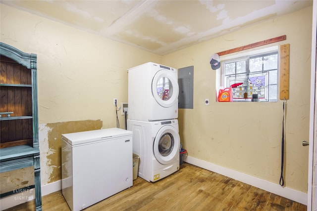 clothes washing area featuring light hardwood / wood-style floors, stacked washing maching and dryer, and electric panel