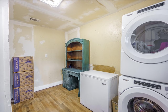 clothes washing area featuring light hardwood / wood-style floors and stacked washer / dryer