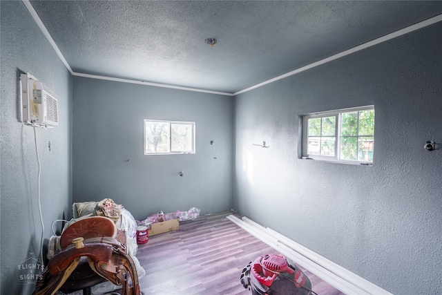 unfurnished bedroom with a textured ceiling, hardwood / wood-style flooring, an AC wall unit, and crown molding