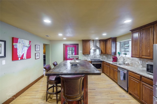 kitchen featuring appliances with stainless steel finishes, backsplash, sink, wall chimney range hood, and a center island