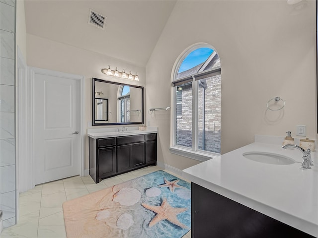 bathroom with marble finish floor, two vanities, visible vents, vaulted ceiling, and a sink