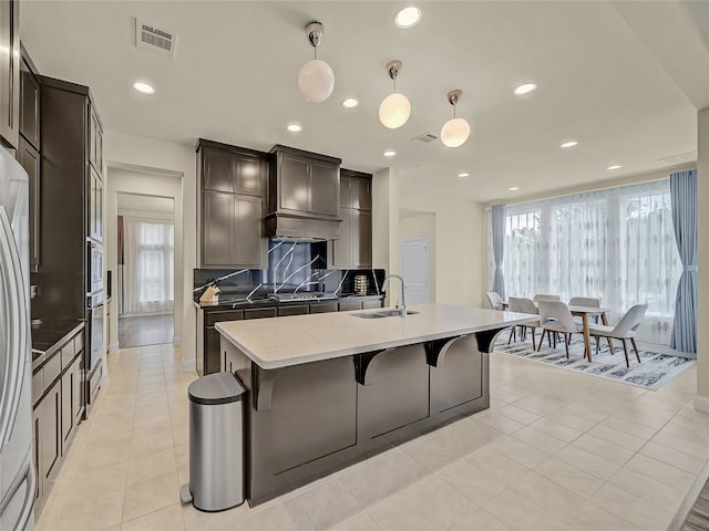 kitchen featuring light tile patterned floors, backsplash, sink, and hanging light fixtures