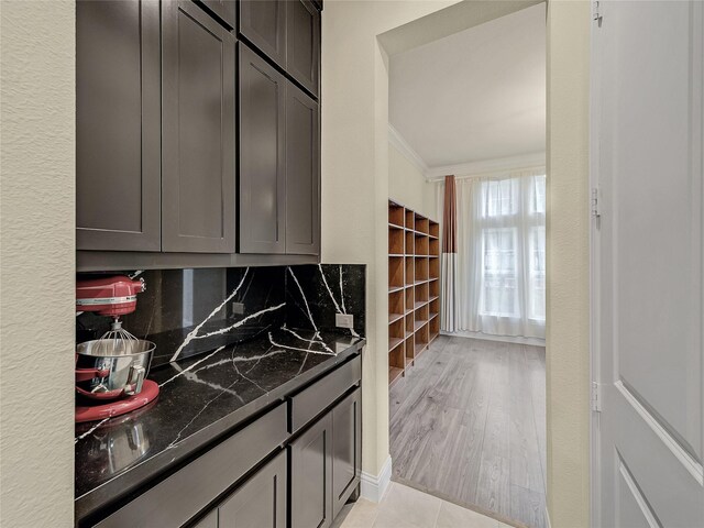 kitchen featuring light hardwood / wood-style floors, dark stone countertops, ornamental molding, and decorative backsplash