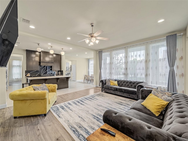 living area with light wood-type flooring, baseboards, visible vents, and recessed lighting