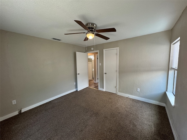 empty room featuring ceiling fan, a textured ceiling, and carpet flooring