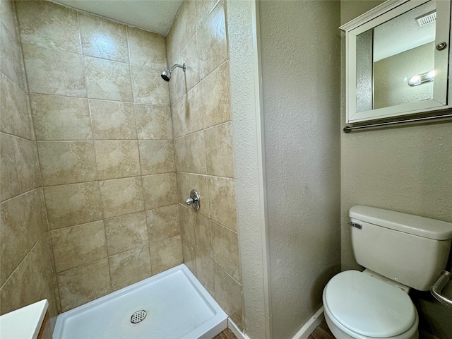 bathroom featuring toilet, a tile shower, and vanity