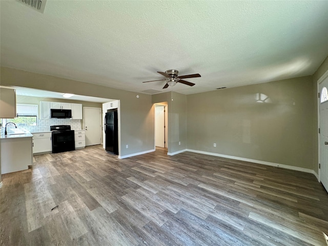 unfurnished living room featuring sink, ceiling fan, a textured ceiling, and wood-type flooring