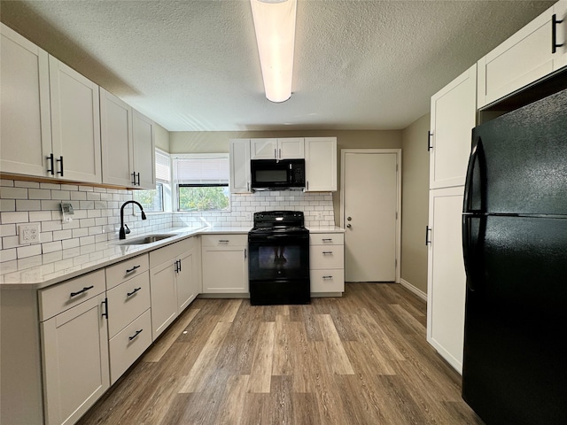 kitchen with sink, light hardwood / wood-style flooring, decorative backsplash, white cabinetry, and black appliances